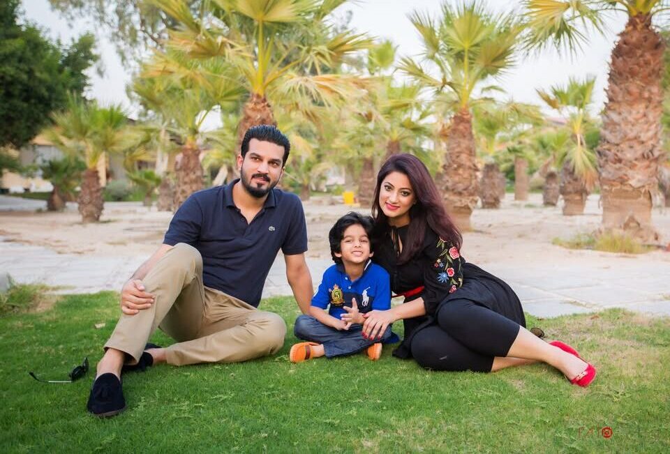 Family sitting on green grass enjoying an outdoor photo session in Dubai.