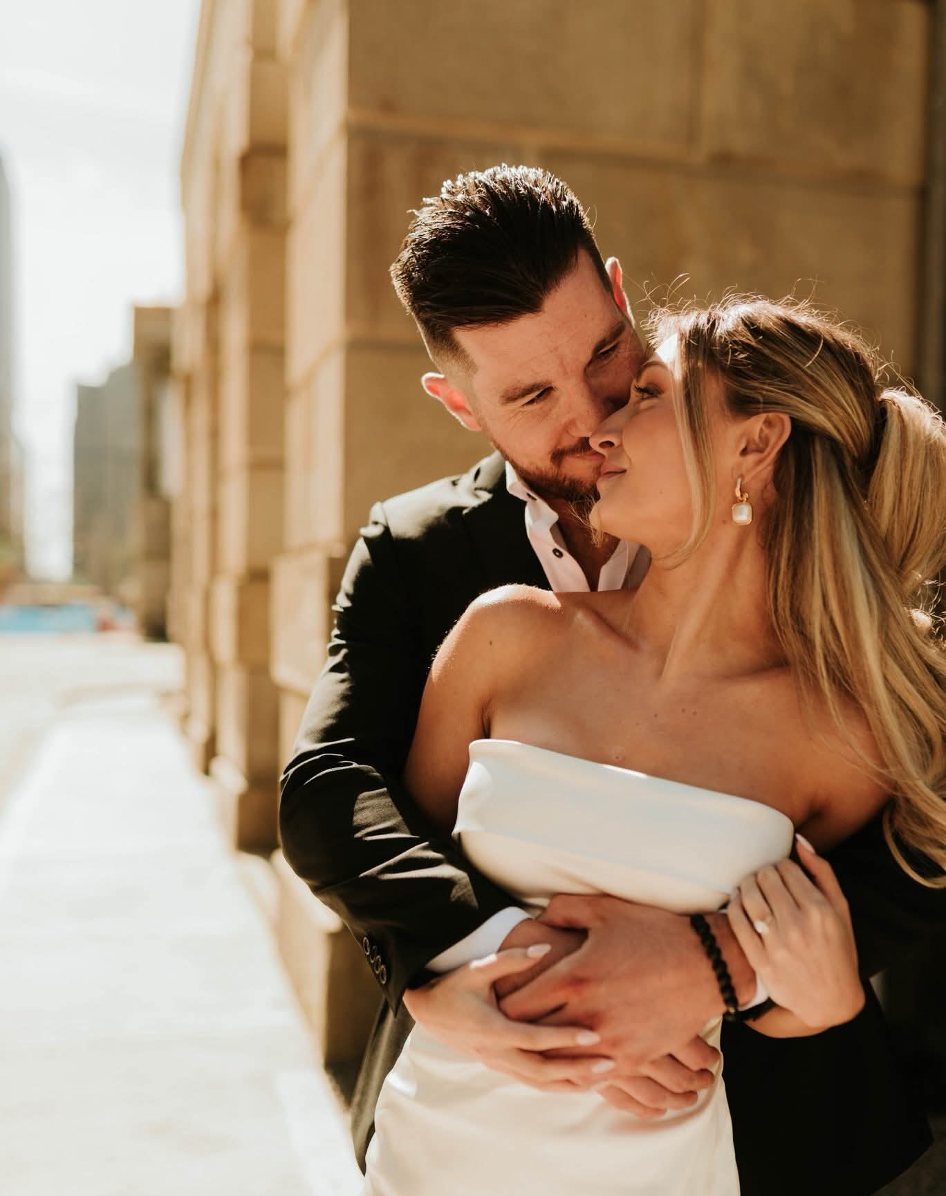 Groom giving a side hug to bride in front of a city tower during Fatography pre wedding photography