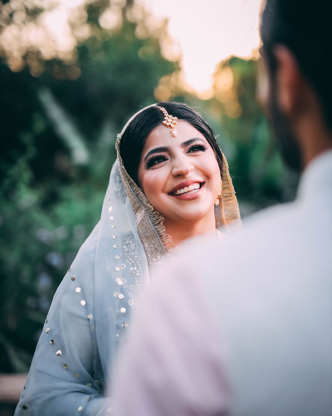 Couple sitting on grass close together in garden pre-wedding shoot