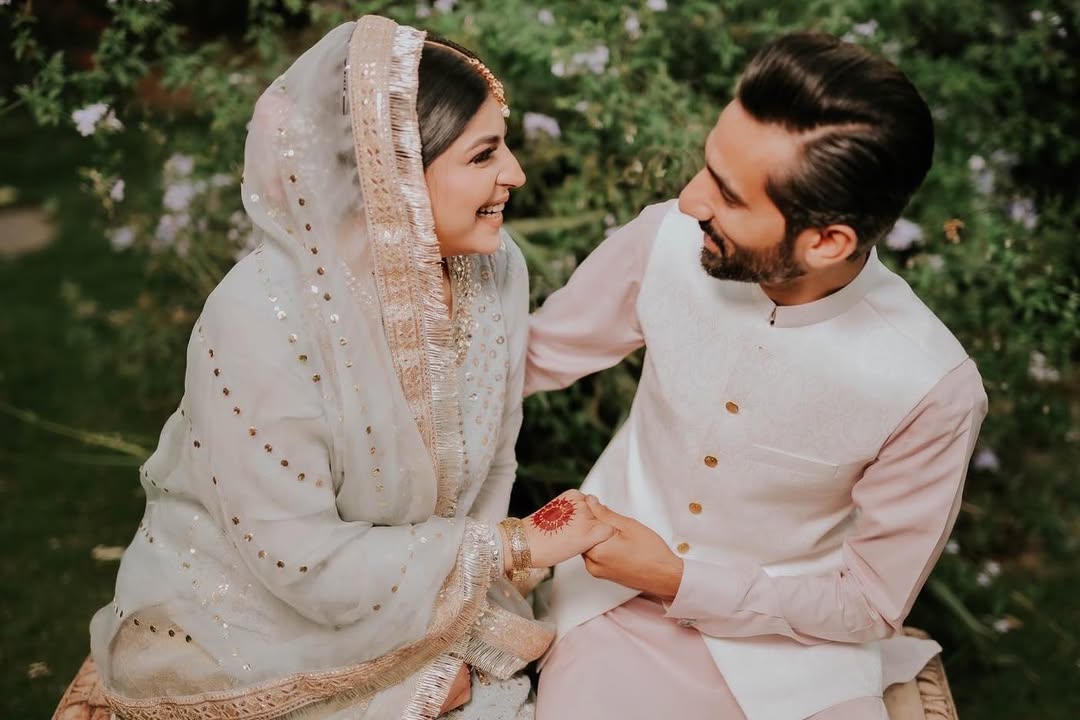 Boy whispering something in girl’s ear during garden pre-wedding shoot