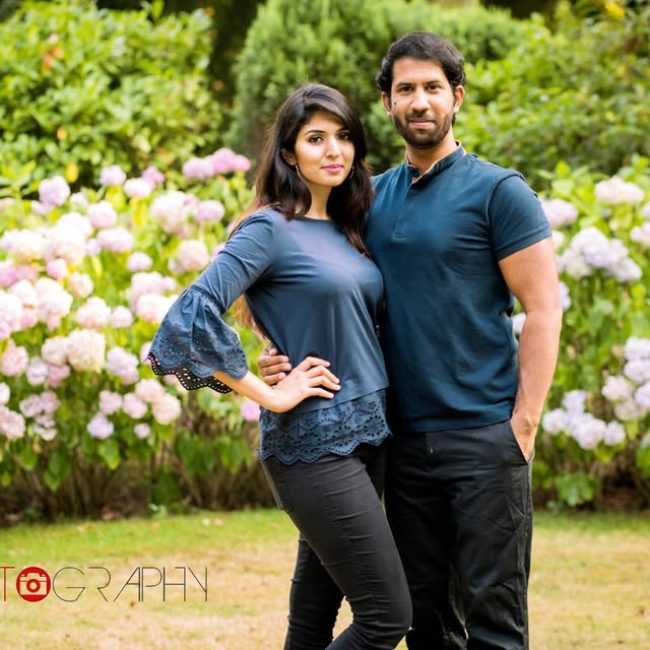 Couple standing together outdoors near a fountain during professional photoshoot.