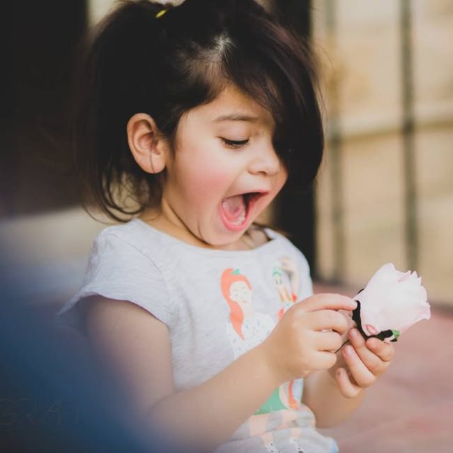 Young girl smiling and holding toy outdoors
