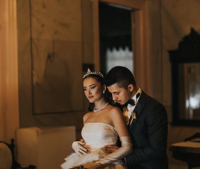 Bride in gown and groom in suit walking beside modern city towers during Fatography pre wedding shoot.