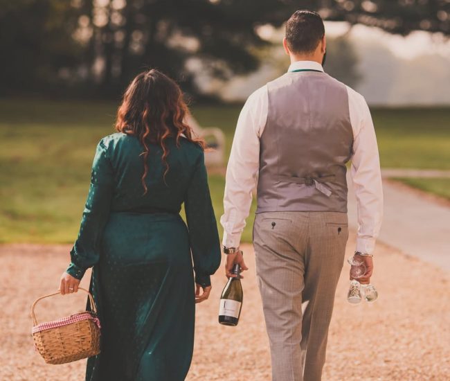 The bride and groom walking directly toward the camera, a large historical building and a green lawn