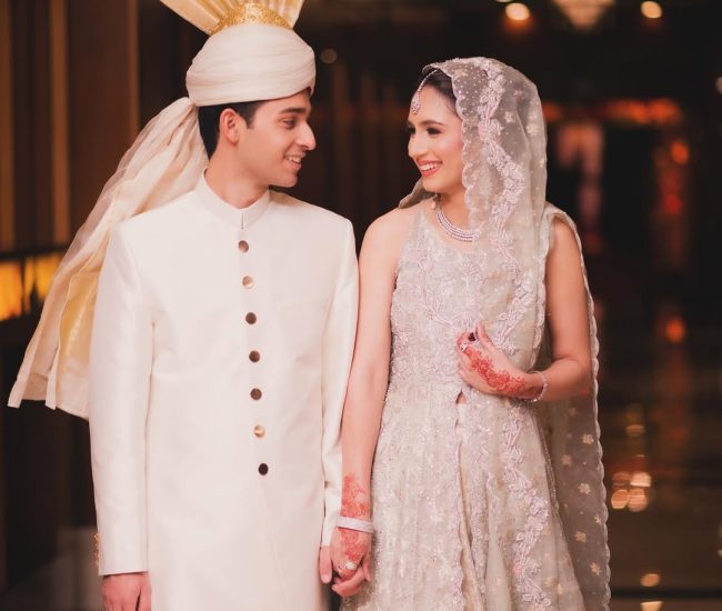 Couple walking hand in hand in decorated marriage hall aisle