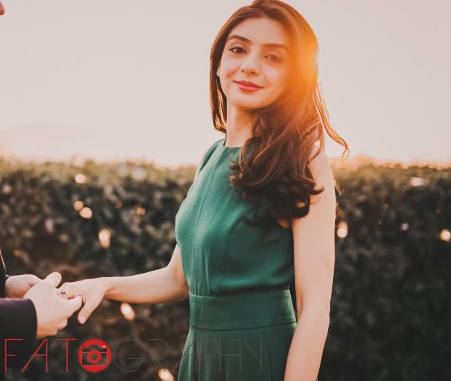 The bride and groom standing together in a wide shot, with the groom looking at the bride, and city lights visible in the background.