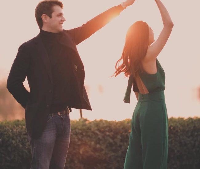 The couple standing together and looking directly at the camera, with the bride's elegant green dress standing out against the natural backdrop.