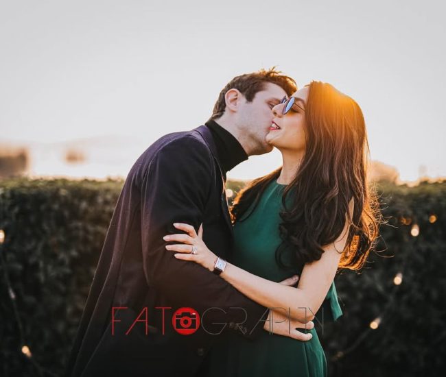 The bride and groom sharing a passionate kiss, silhouetted against a beautiful sunset sky.