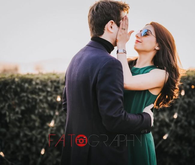 A side portrait of the couple standing close together, with the groom looking at the bride, who is looking at the camera.