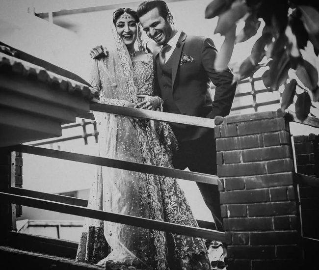 Pre-wedding couple walking barefoot on green grass in garden