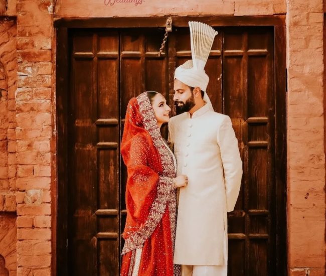 Pre-wedding photoshoot of couple sitting on traditional mud house roof in village