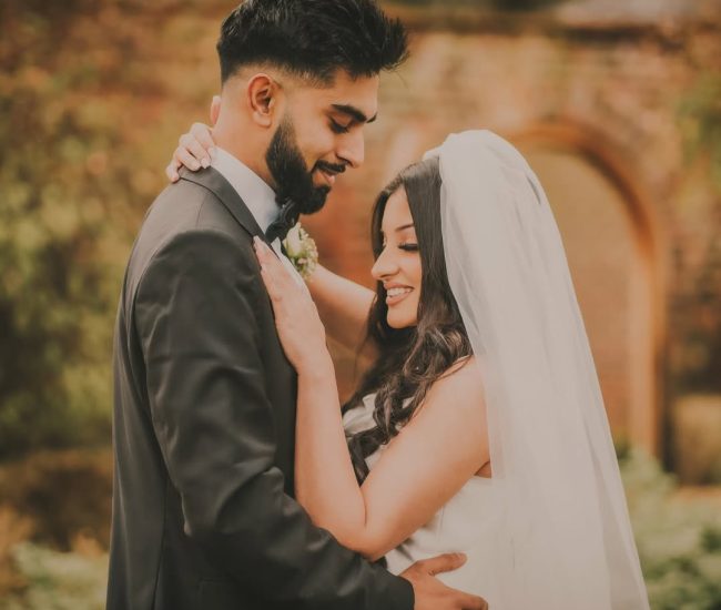 Couple posing together near stone wall during outdoor pre-wedding shoot