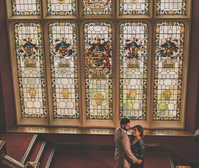 A formal portrait of the engaged couple standing close together, with classical architecture providing a timeless backdrop for their photos.
