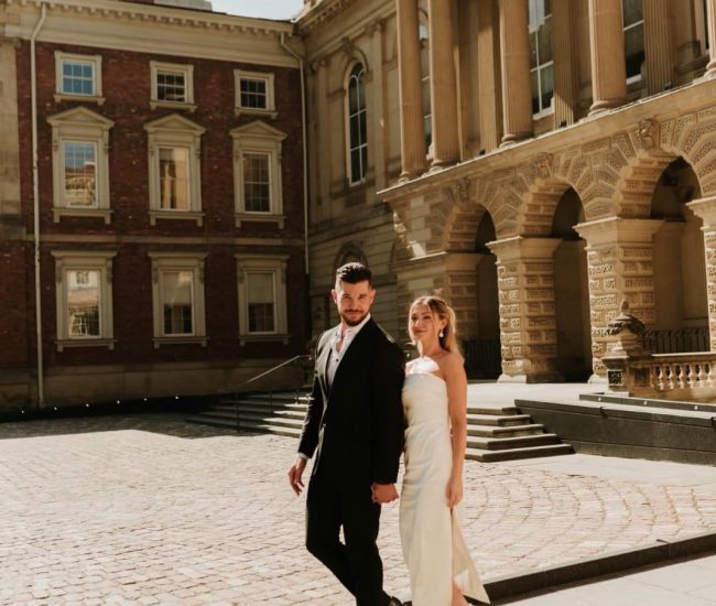 Couple walking casually in front of urban buildings during a Fatography pre wedding photoshoot.