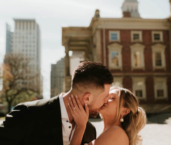 Bride and groom sitting together beside a modern building during a Fatography pre wedding shoot