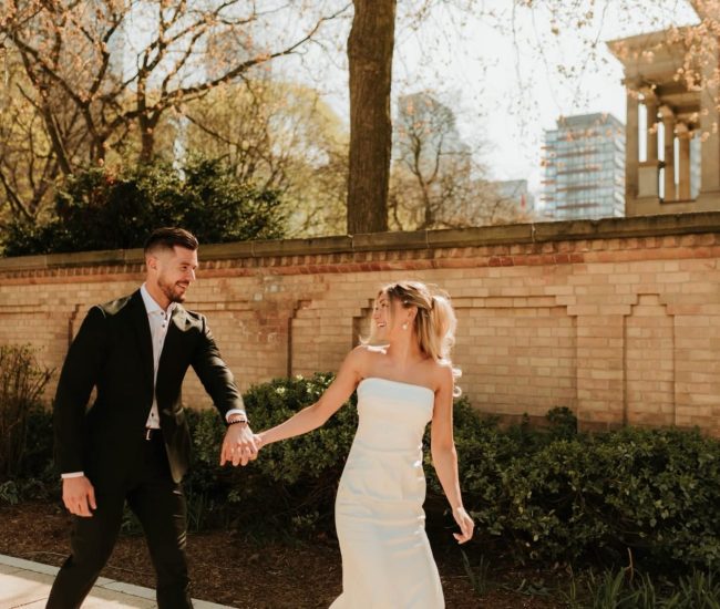 Bride leaning on groom near modern architecture during Fatography pre wedding shoot.