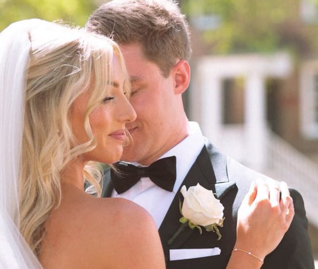 The groom gently kissing the bride's cheek in a loving, candid moment during their wedding day portraits.
