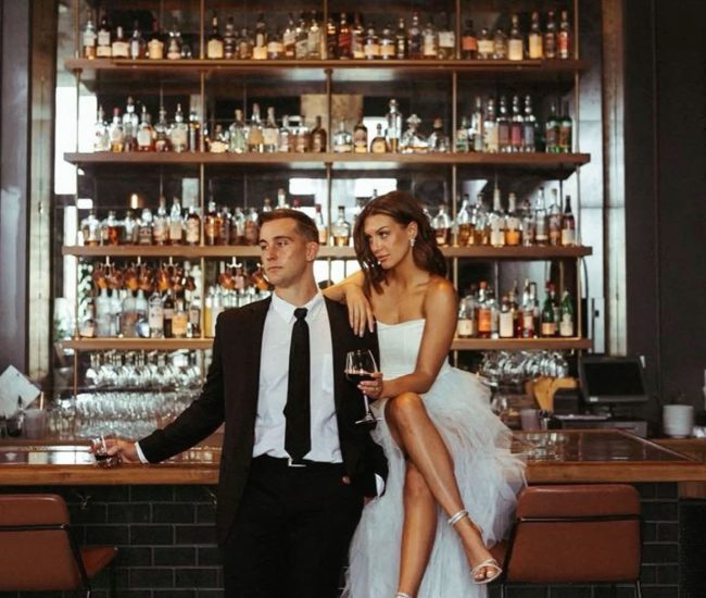 Groom gently holding bride’s face near city architecture during Fatography pre wedding photoshoot